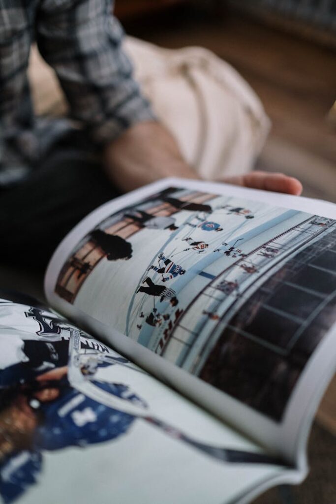 A close-up shot of a person reading a magazine with images of ice hockey scenes indoors.