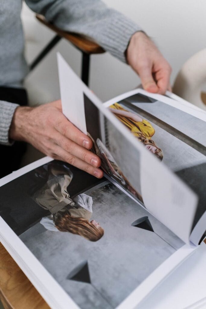 Close-up of hands flipping through a fashion magazine indoors, featuring stylish photography.